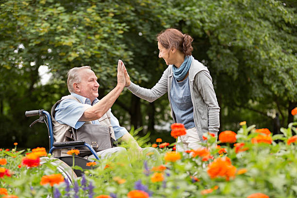 caregiver and senior man on a wheelchair, walking in park - wheelchair disabled senior adult female nurse imagens e fotografias de stock