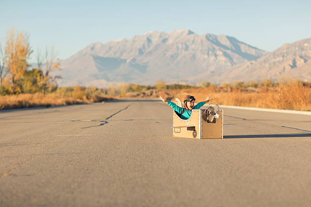 istock Young Boy with Goggles Imagines Flying in Cardboard Airplane 599282258