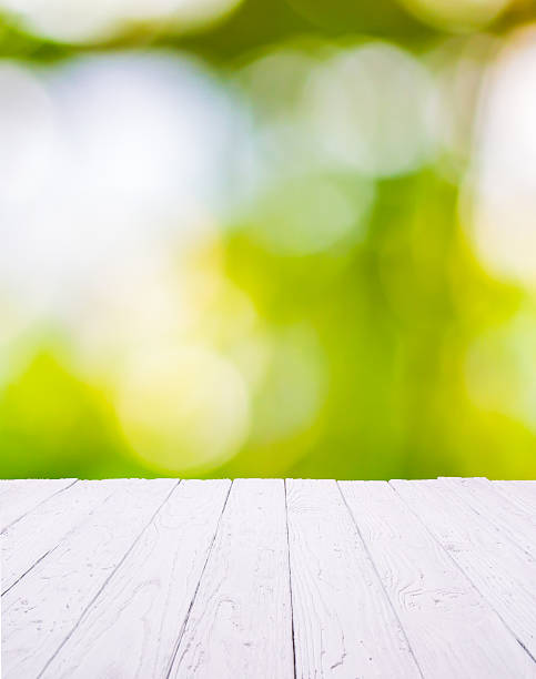 istock White wooden table with green bokeh background 599282626