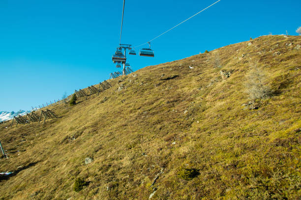 A ski slope in Sölden, Austria, without snow, due to climate change. People are riding up the mountain in the ski lift.  XXXL size image taken with Canon 5Ds.