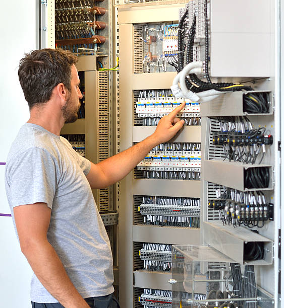 istock Electrician Looking in Fuse Box in Electrical Room 599461834