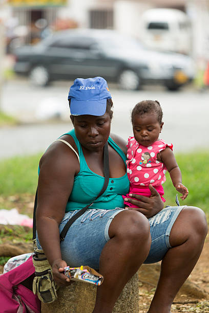 Poor Colombian woman and her daughter begging in Salento, Colomb Salento, Colombia - March 7, 2015: Afro Colombian woman holding her child in her arms and begging in the street of Salento. Colombia 2015 family mother poverty sadness stock pictures, royalty-free photos & images