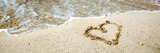 istock Heart symbol on the sand and sea wave. 599463118