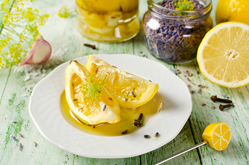 Preserved lemons with salt, lavender, garlic and cloves on a wooden table and spices on background
