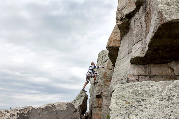 istock man trying to climb up a cliff with no equipment 599467536