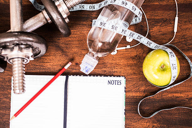 istock Fitness, exercise themed scene with weights, earbuds, apple, journal. 599470596