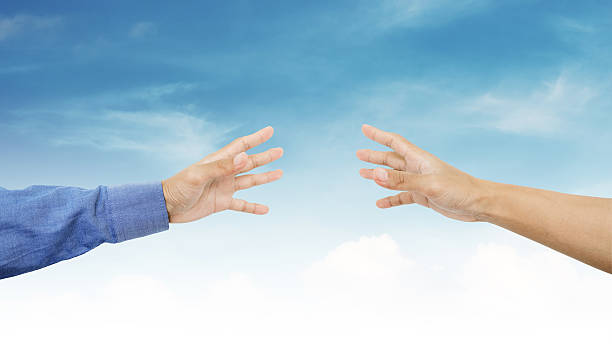istock Hands reaching together on blue sky background 599474978