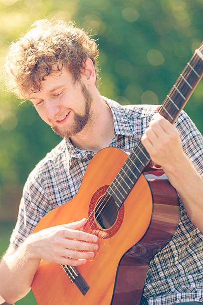 istock Young man camping playing guitar outdoor 599475604