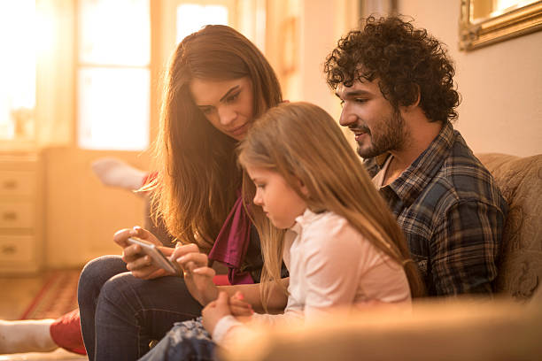 istock Young parents using smart phone with their daughter at home. 599484128