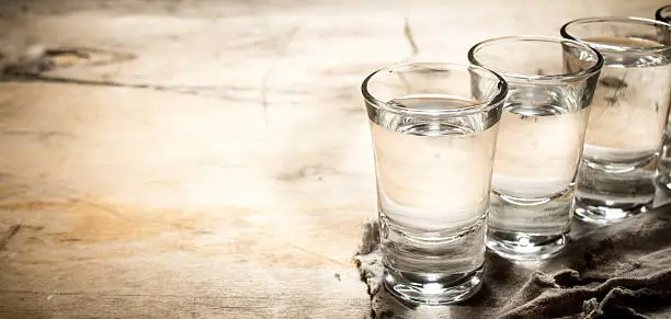 The vodka glass. On a wooden background.