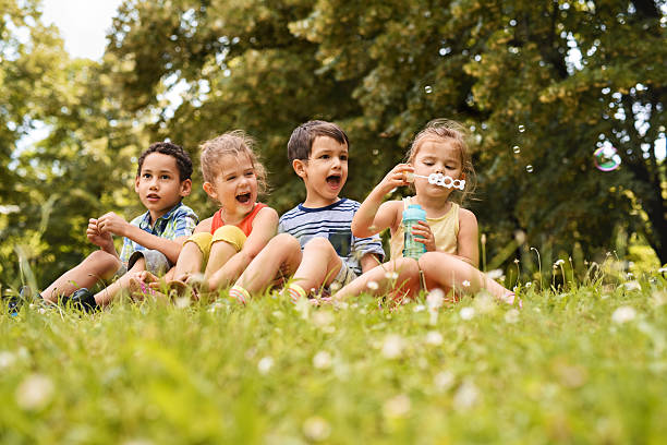 istock Group of small kids relaxing in grass at the park. 599487946