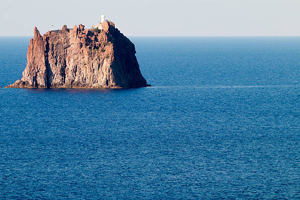 A tiny lighthouse perched on the sea stack of Strombolicchio in the Italian Aeolian islands