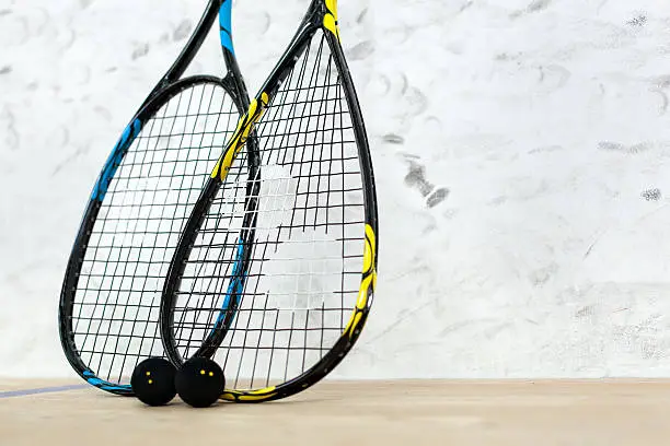 Photo of Two tennis rackets and balls standing by the wall