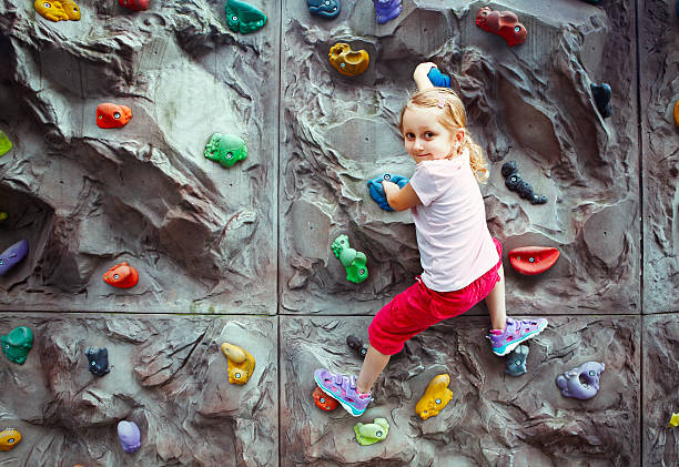 Determined boy practicing rock climbing in fitness studio