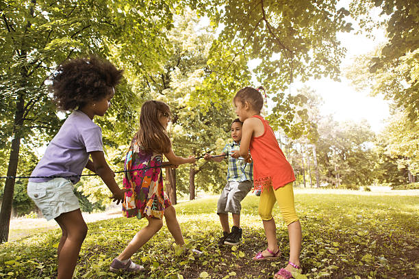 istock Small group of children pulling a rope in nature. 599490860