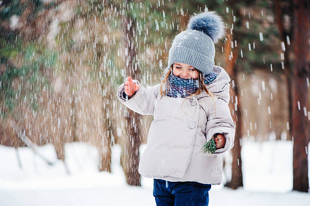 cute happy baby girl playing in snowy winter forest cute happy toddler girl playing in outdoor snowy winter forest, seasonal activities for kids kids winter fashion stock pictures, royalty-free photos & images