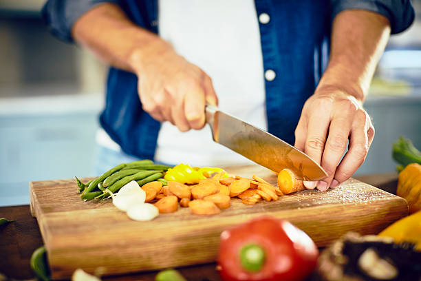 istock Midsection of male cutting carrot on chopping board in kitchen 599493478