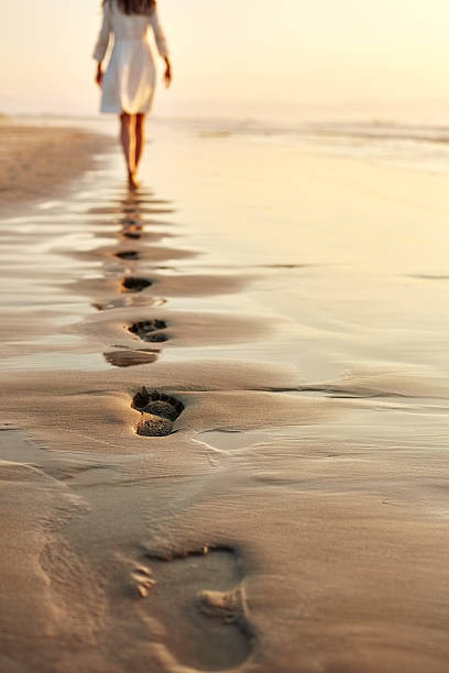 mujer caminando descalzo en húmedo dejar huellas en la arena la costa - footprint sand sea beach fotografías e imágenes de stock
