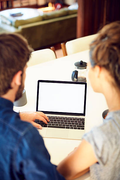 istock Over the shoulder of couple using laptop with blank screen 599501580
