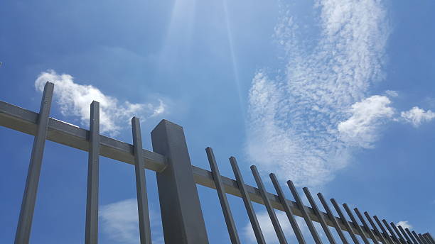 istock gray painted metal fence with blue sky background 599504116
