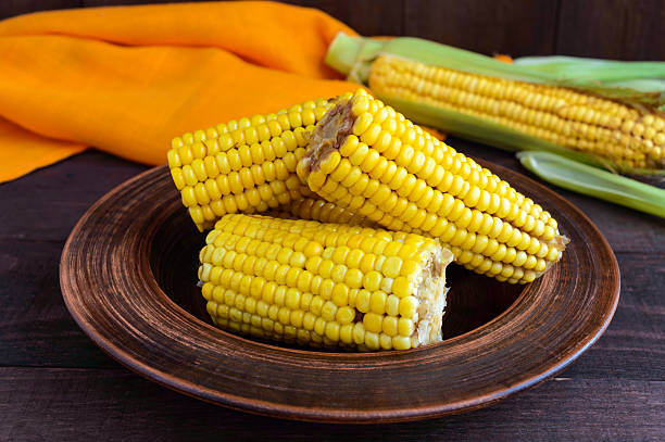 istock Cooked and raw corncobs on a dark wooden background. 599505056