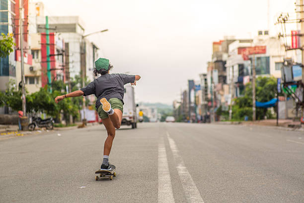 A back shot of a girl skateboarding down a long city street in the early morning.