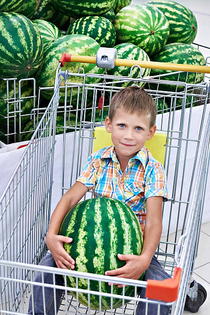 istock Boy with watermelon sitting in shopping cart 599676640