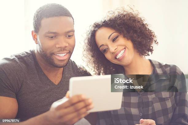 Happy Afro American Couple Using A Digital Tablet At Home Stock Photo - Download Image Now