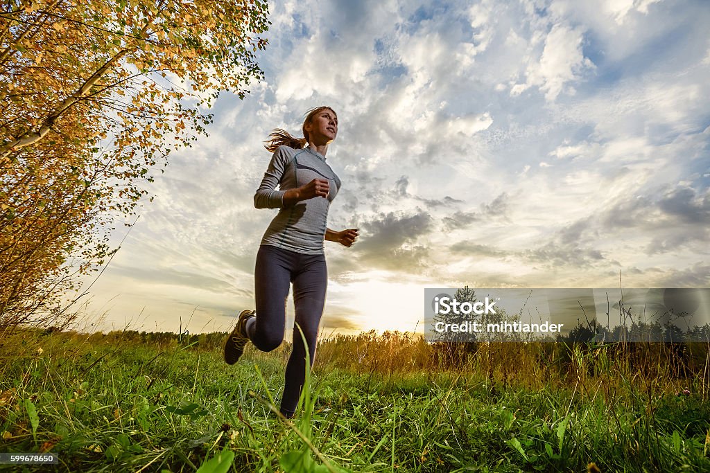 Runner in the forest Slim lady running in the autumn forest Cross-Country Running Stock Photo