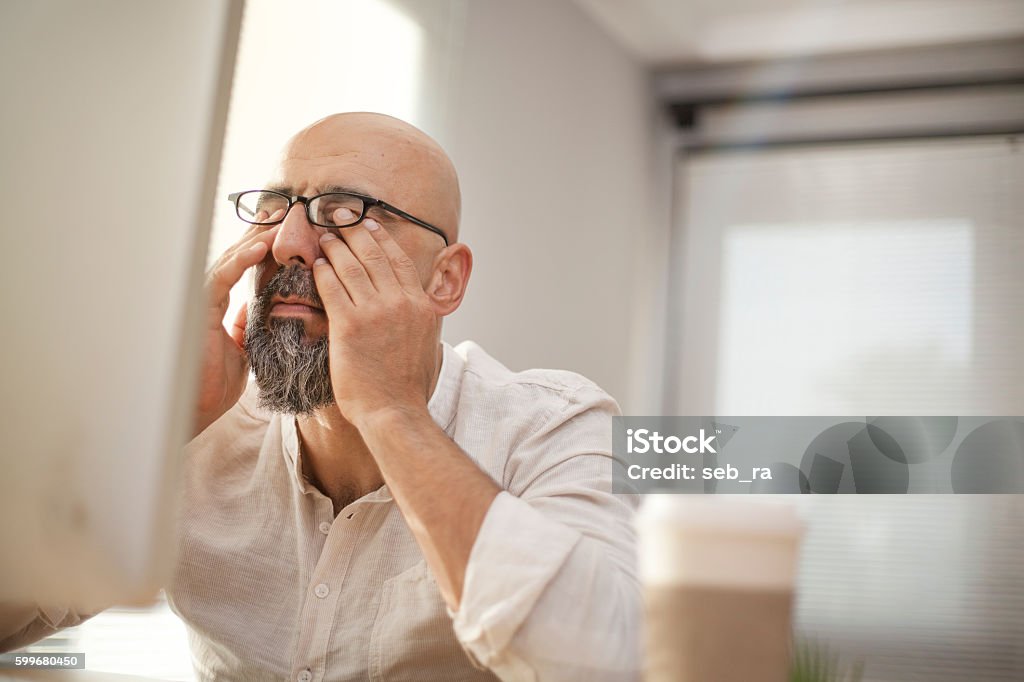 Senior businessman rubbing his tired eyes Tired Stock Photo