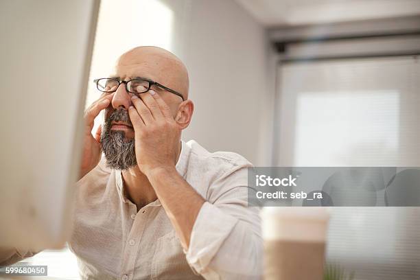 Senior Businessman Rubbing His Tired Eyes Stock Photo - Download Image Now - Tired, Working, Men