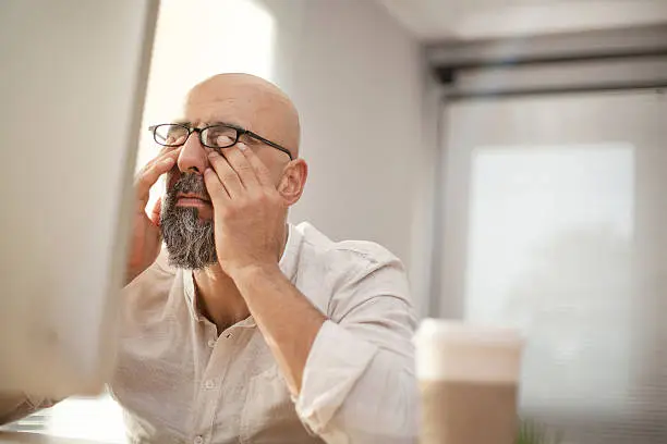 Senior businessman rubbing his tired eyes