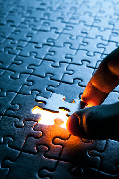 Hand inserting missing puzzle piece stock photo