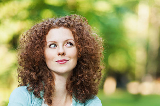 夢を見ている若い女性が見上げる - nature curly hair smiling human face ストックフォトと画像