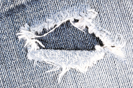 Frayed blue jeans closeup with copy space