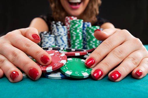 Young woman holding gambling chips on black background