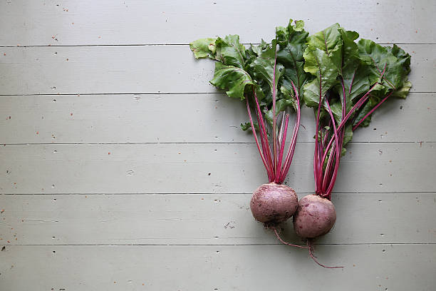 Two beetroots together on a pale green wooden floor