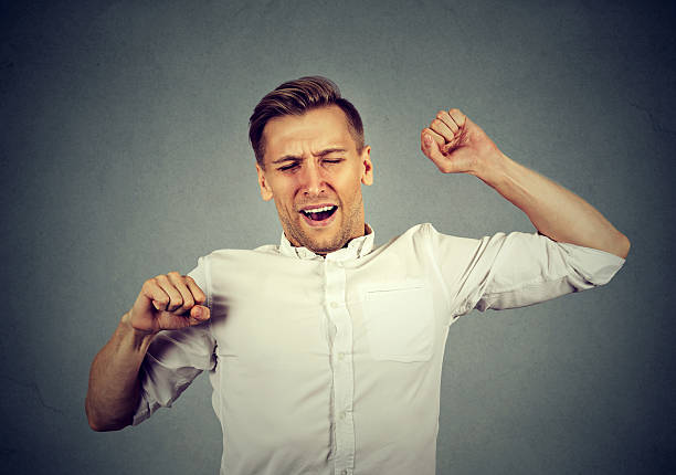 istock Young sleepy man yawning stretching arms back 599695140