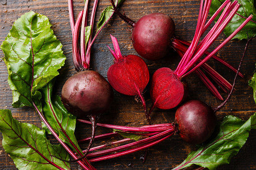 Red Beetroot with herbage green leaves on wooden background