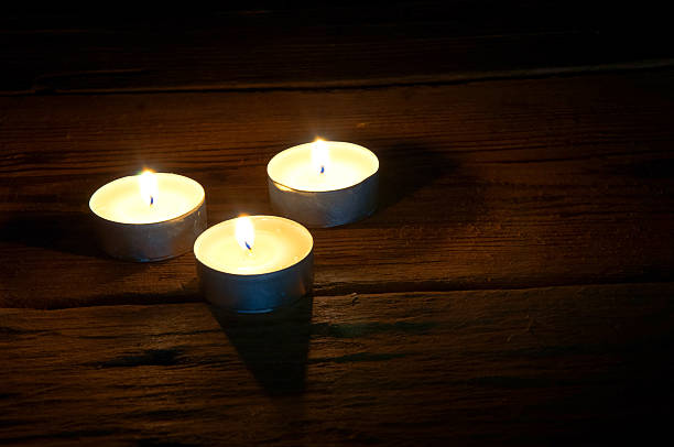 istock Burning tealights on dark wooden background. Copyspace 599697312