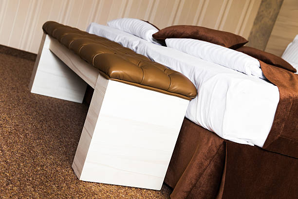 Brown upholstered leather footstool on a bed stock photo