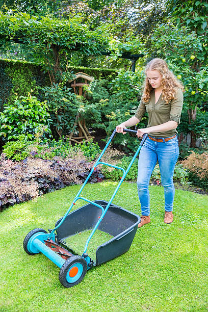 istock Young dutch woman pushing lawn mower on grass 599700254