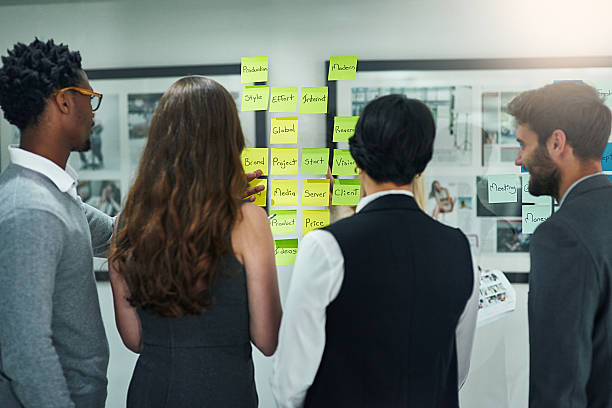 最も成功したアイデアはチームとして策定されます - adhesive note rear view business meeting ストックフォトと画像