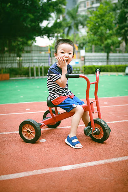 Three wheel vintage bike on stone paved sidewalk. 1940s retro-styled tricycle child wrought iron bicycle, rusty pedal, wooden saddle, damaged tire.