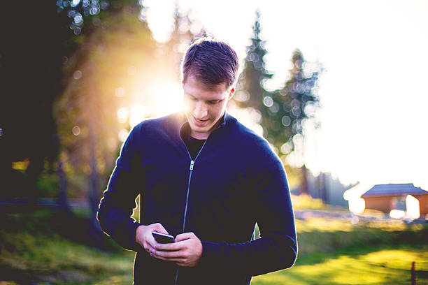 portrait of a man, using smartphone in the middle of a forest - young male fotos imagens e fotografias de stock