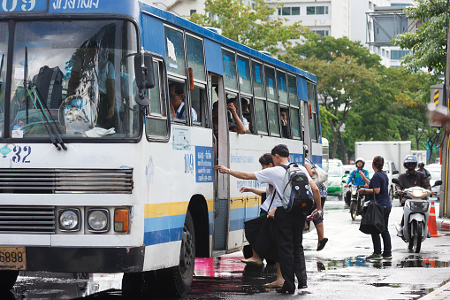 Bangkok, Thailand - August 21, 2015: People getting on a bus on Rama IV Rd. after the rain, Public bus is major transportation in Bangkok because it is most covered routes and cheap fare tickets