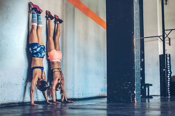 Women performing handstand in gym.  Professional sportists. Wearing sports clothing.