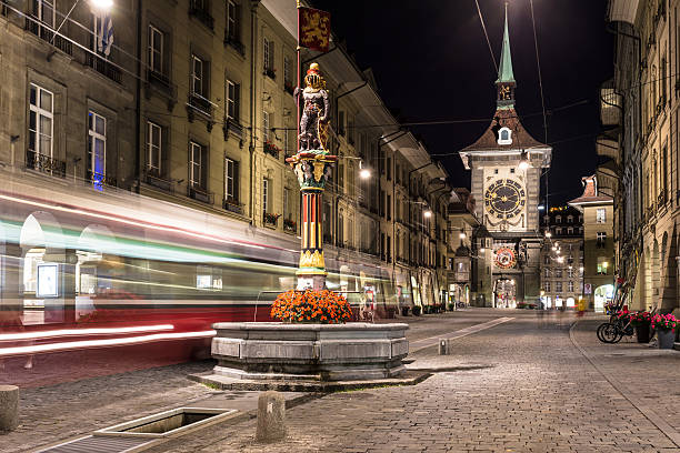 Tram rushes in the street of Bern A tram rushes through the streets of Bern old town with the Zytgolgge tower in the background in Switzerland capital city at night. blurred motion street car green stock pictures, royalty-free photos & images