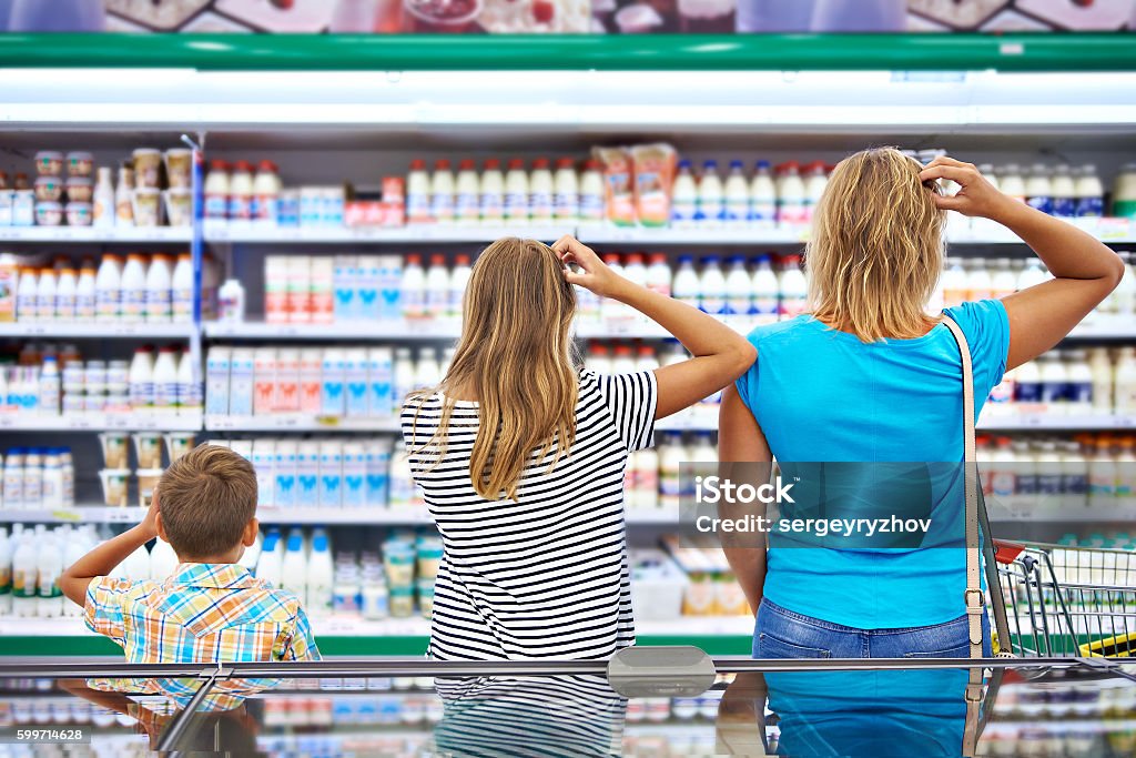 Family chooses dairy products in shop Mother and children are choosing dairy products in shop Confusion Stock Photo