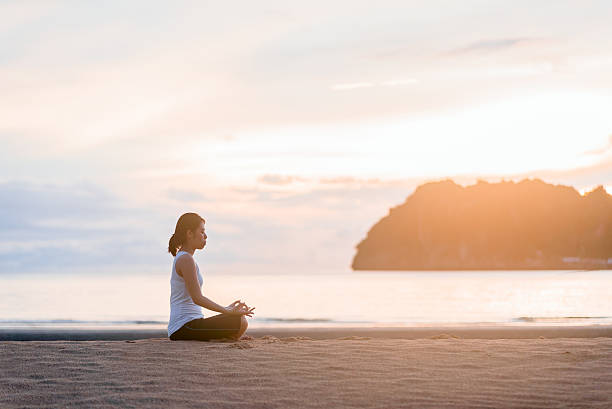 istock Young woman practicing yoga on the beach at sunset. 599715108